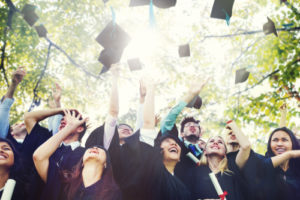 Studenten feiern ihren Abschluss und werfen ihre Hüte in die Luft