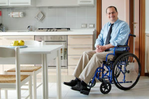 Ein Mann mit Krawatte im Rollstuhl in seiner Wohnküche