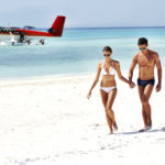 Ein Paar am Sandstrand mit Wasserflugzeug im Hintergrund