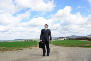 Ein Mann im Anzug mit Aktenkoffer auf einem Feldweg