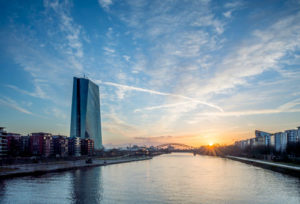 Das neue Hauptgebäude der EZB bei Sonnenaufgang vor einem strahlend blauen Himmel