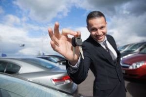 Ein gelackter Autohändler streckt einen Autoschlüssel entgegen