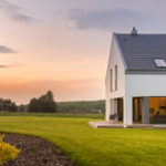 Ein modernes Haus auf einem großen, grünen Grundstück im Sonnenuntergang
