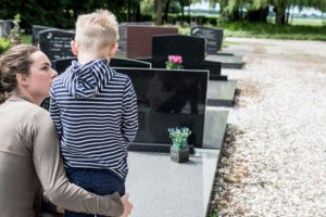 Eine Mutter und ihr Sohn stehen an einem Grab
