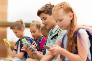 Vier Grundschuldkinder, die mit ihren Smartphones spielen