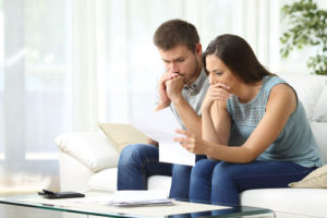 Ein besorgtes Paar auf dem Sofa studiert einen Vertrag