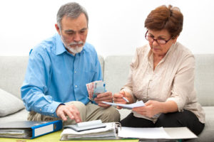 Ein Rentnerpaar liest Akten und rechnet nach