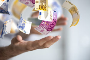 Eine offene Hand wirft viele Euro Scheine in die Luft